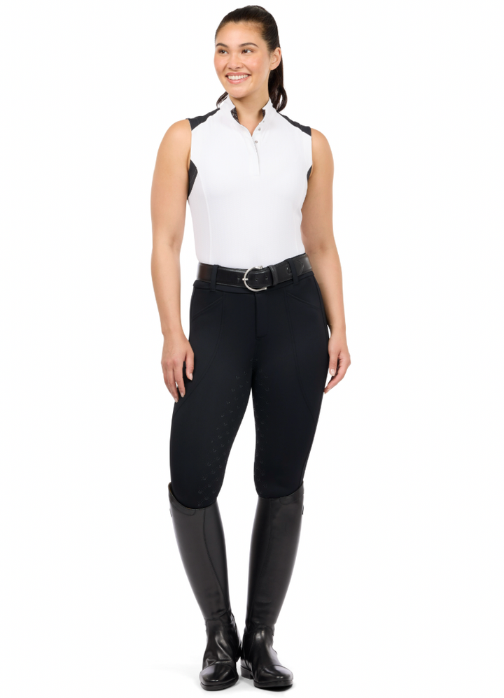 Woman wearing a white sleeveless shirt, black riding pants, and black riding boots on a white background