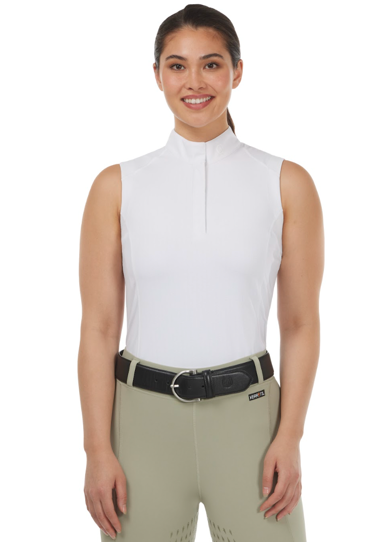 Woman wearing a white sleeveless top and beige riding pants with a black belt.