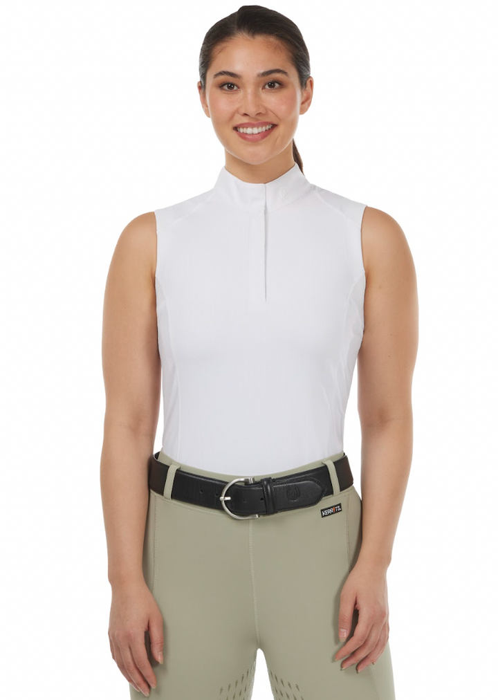 Woman wearing a white sleeveless top and beige riding pants with a black belt.