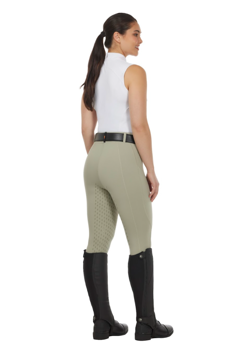 Woman wearing equestrian pants and boots on a white background
